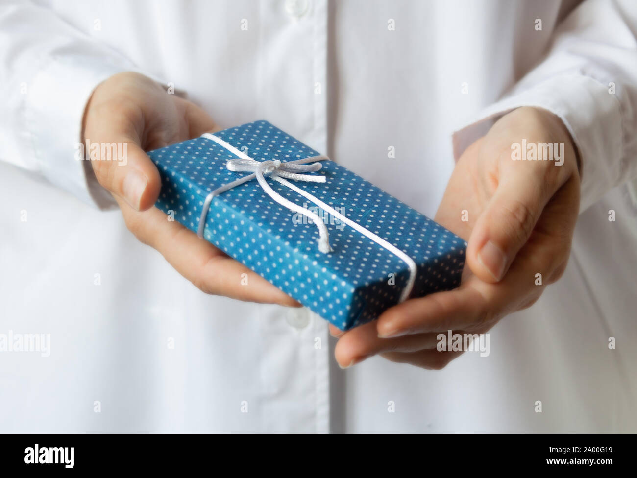 La donna in bianco manto medico tenendo scatola regalo decorata in carta artigianale in mani. Messa a fuoco selettiva. Natale e Anno Nuovo concetto. Foto Stock