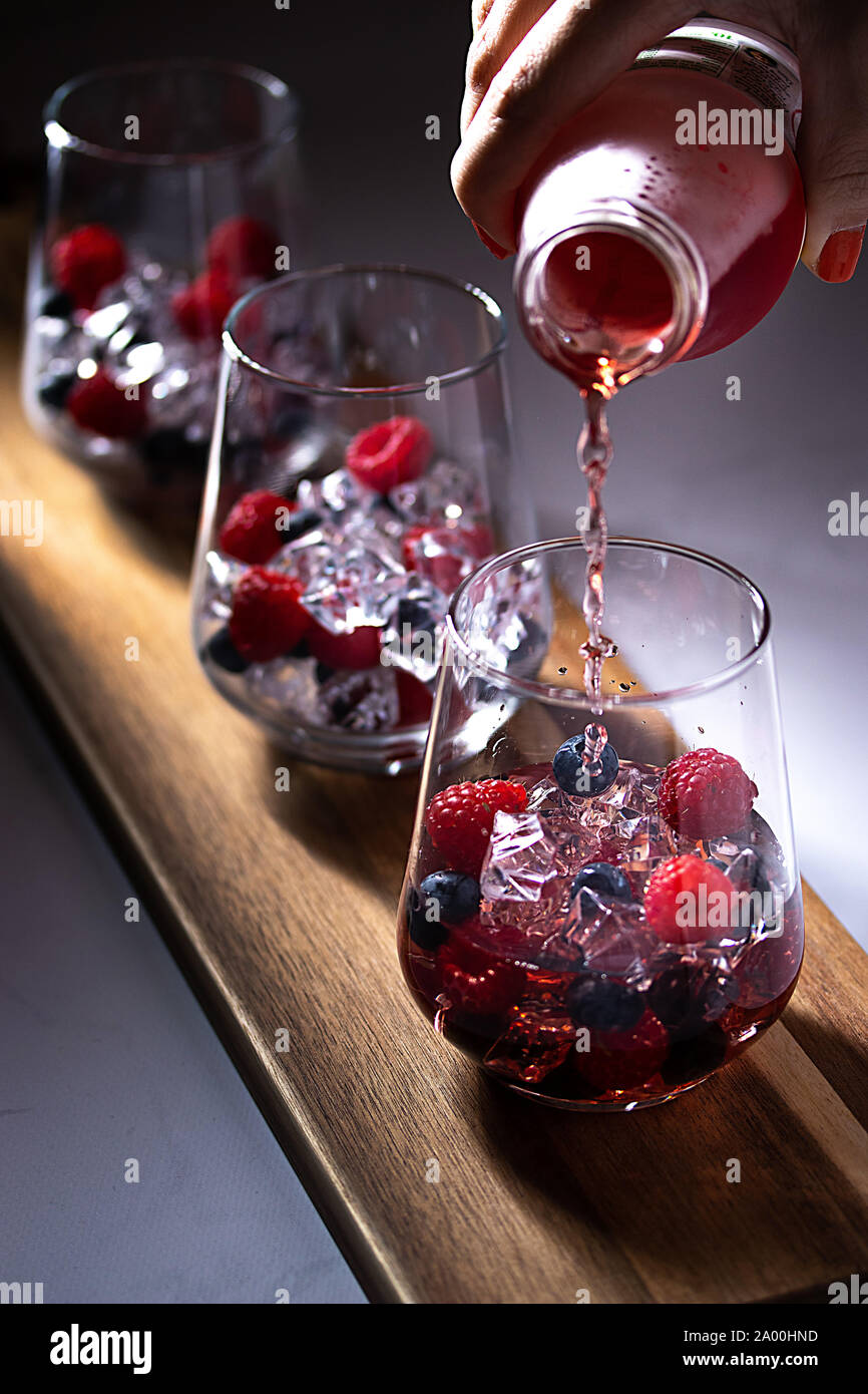 Bevanda versata in bicchieri con frutti di bosco Foto Stock