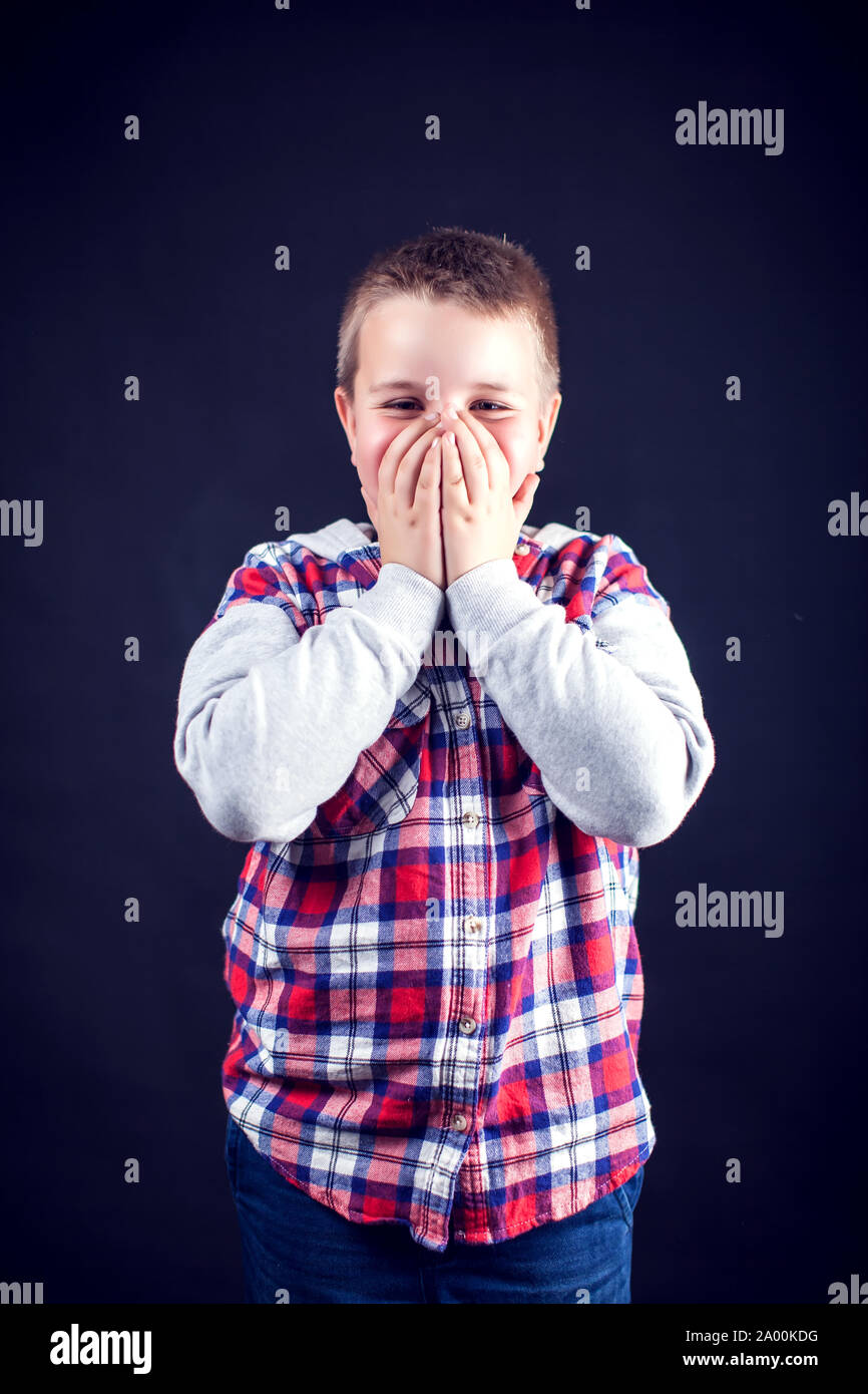 Un ragazzo chiuso la bocca con le mani. I bambini e le emozioni concetto Foto Stock
