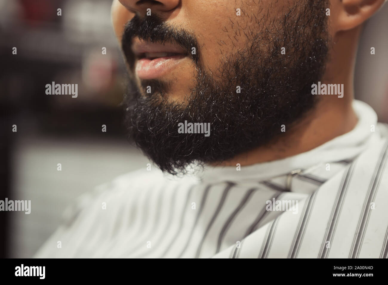 Giovane uomo nero con barba lunga barba in seduta Barbieri Presidente  coperto con coperta in attesa di alta qualità la rasatura.client di  Barberia pronta per il trattamento Foto stock - Alamy