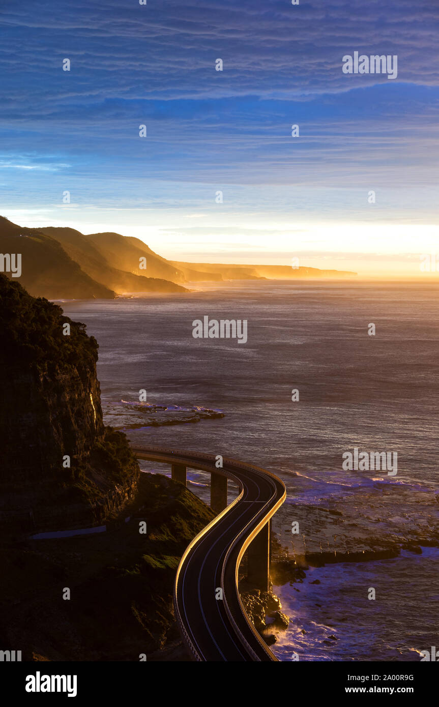 Vista aerea del Sea Cliff bridge all alba e al tramonto con raggi solari e raggi solari. Australian strade e infrastrutture. Gita turistica in St Foto Stock