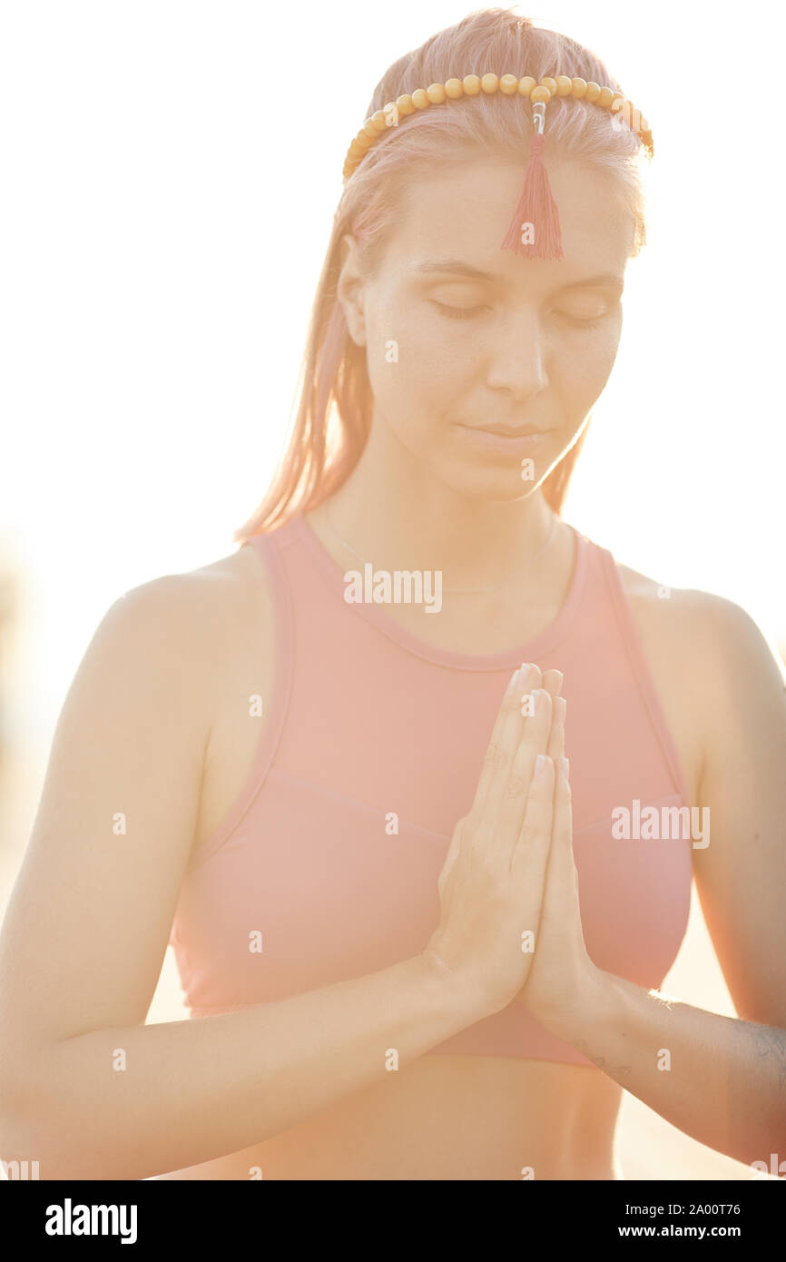 Giovane donna bionda chiuse gli occhi e la pratica dello yoga durante il sunrise all'aperto Foto Stock