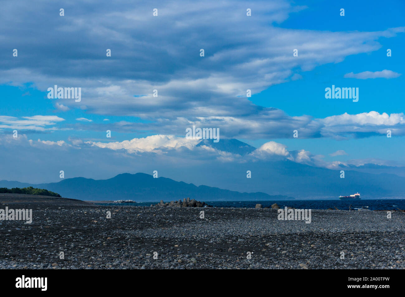 Spiaggia, coste di Shizouka con il Monte Fuji sullo sfondo. Spiaggia rocciosa con sabbia nera vulcanica, ciottoli e acque blu della Baia di Suruga, Pacific co Foto Stock