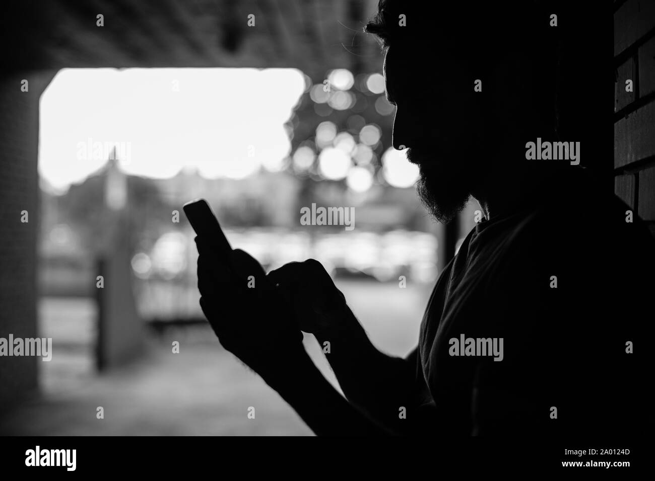 Uomo che guarda il suo telefono mentre si alza nel passaggio buio Foto Stock