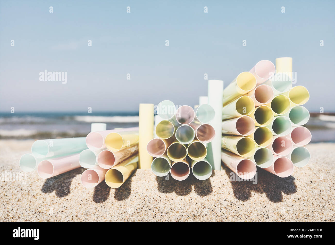 Pile di cannucce di plastica su una spiaggia, plastica inquinamento ambientale concetto, il fuoco selettivo, tonificazione del colore applicato. Foto Stock