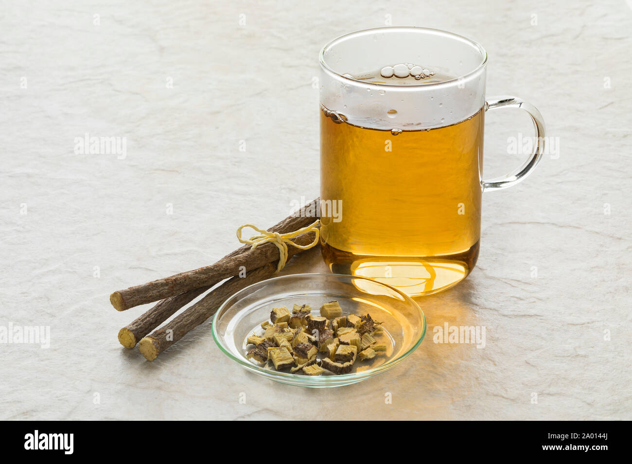 Bicchiere di tè di liquirizia e pezzi di radici nella parte anteriore della tazza Foto Stock