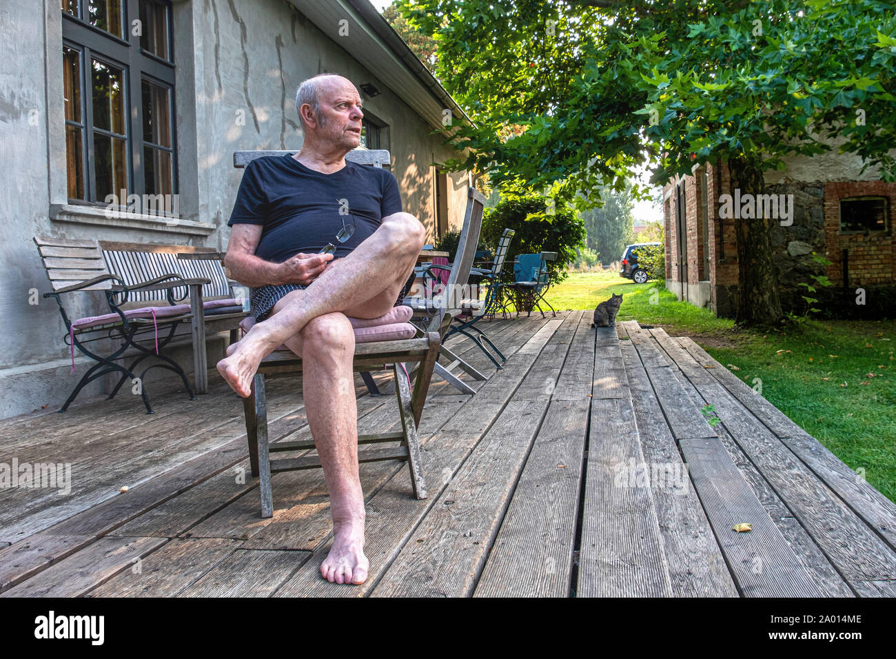 Uomo anziano seduto sul ponte di legno di agriturismo a Pinnow, Uckermark, Brandeburgo, Germania Foto Stock