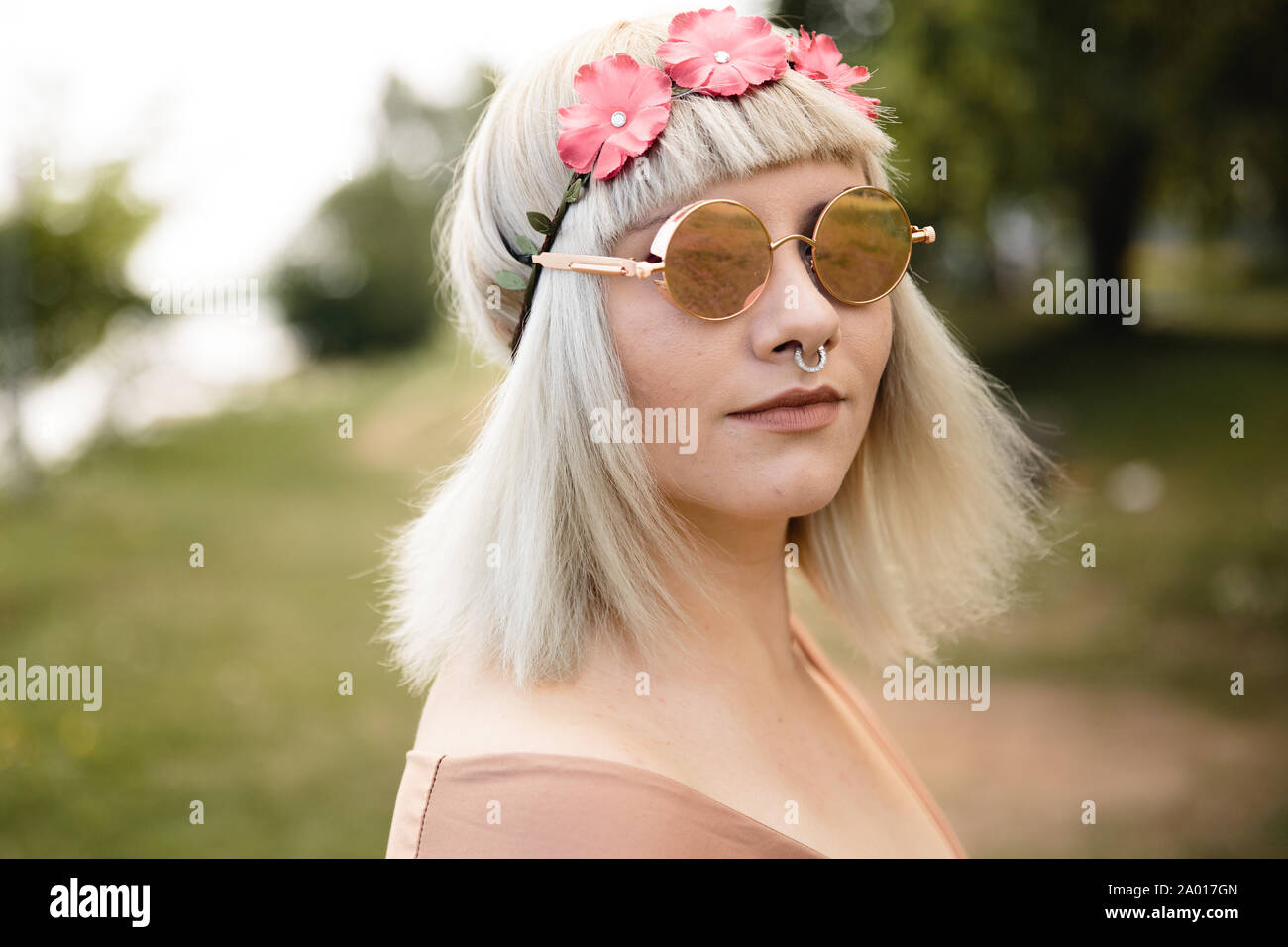 Giovane biondo hippie donna con cuore di occhiali e fiore fuori banda in un  parco Foto stock - Alamy