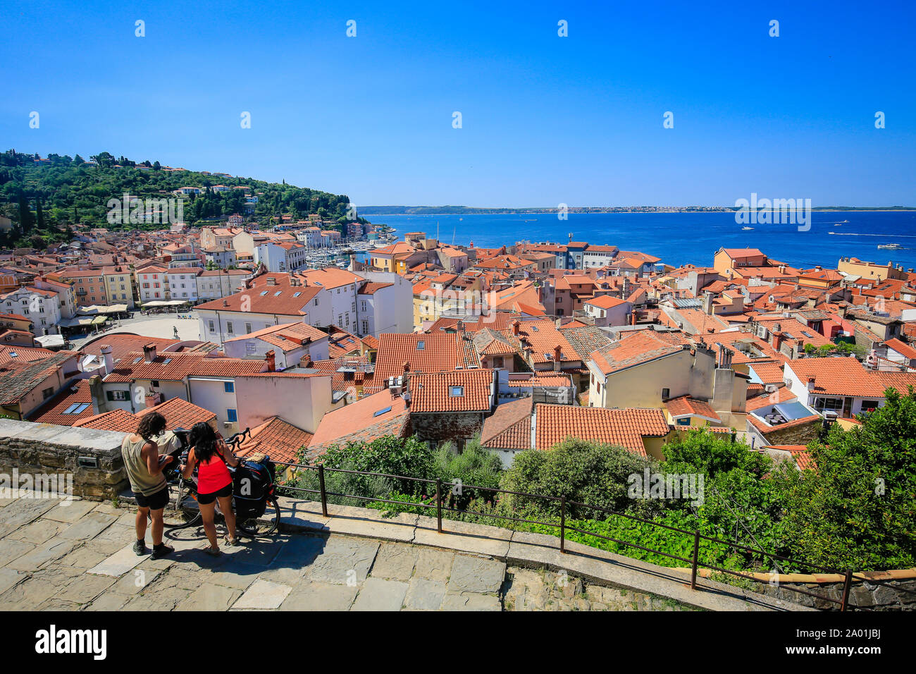 Pirano, Istria, Slovenia - vista città, con vista sui tetti della città portuale sul Mar Mediterraneo ed i ciclisti di fronte. Pirano, Istrien, Slowenien - St Foto Stock