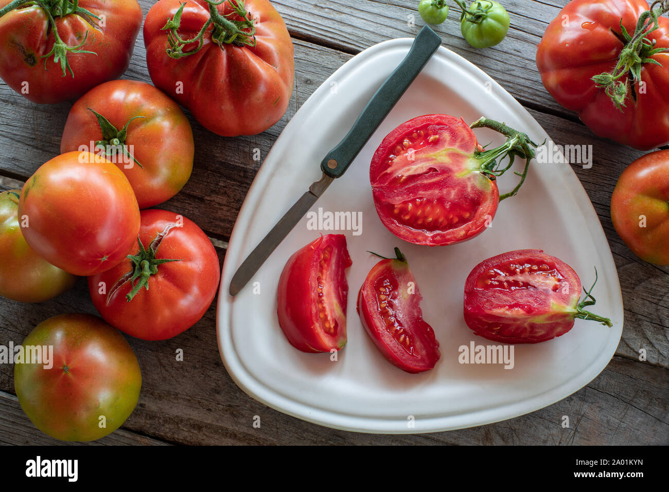 Gruppo di pomodori con fette di pomodoro su piastra Foto Stock