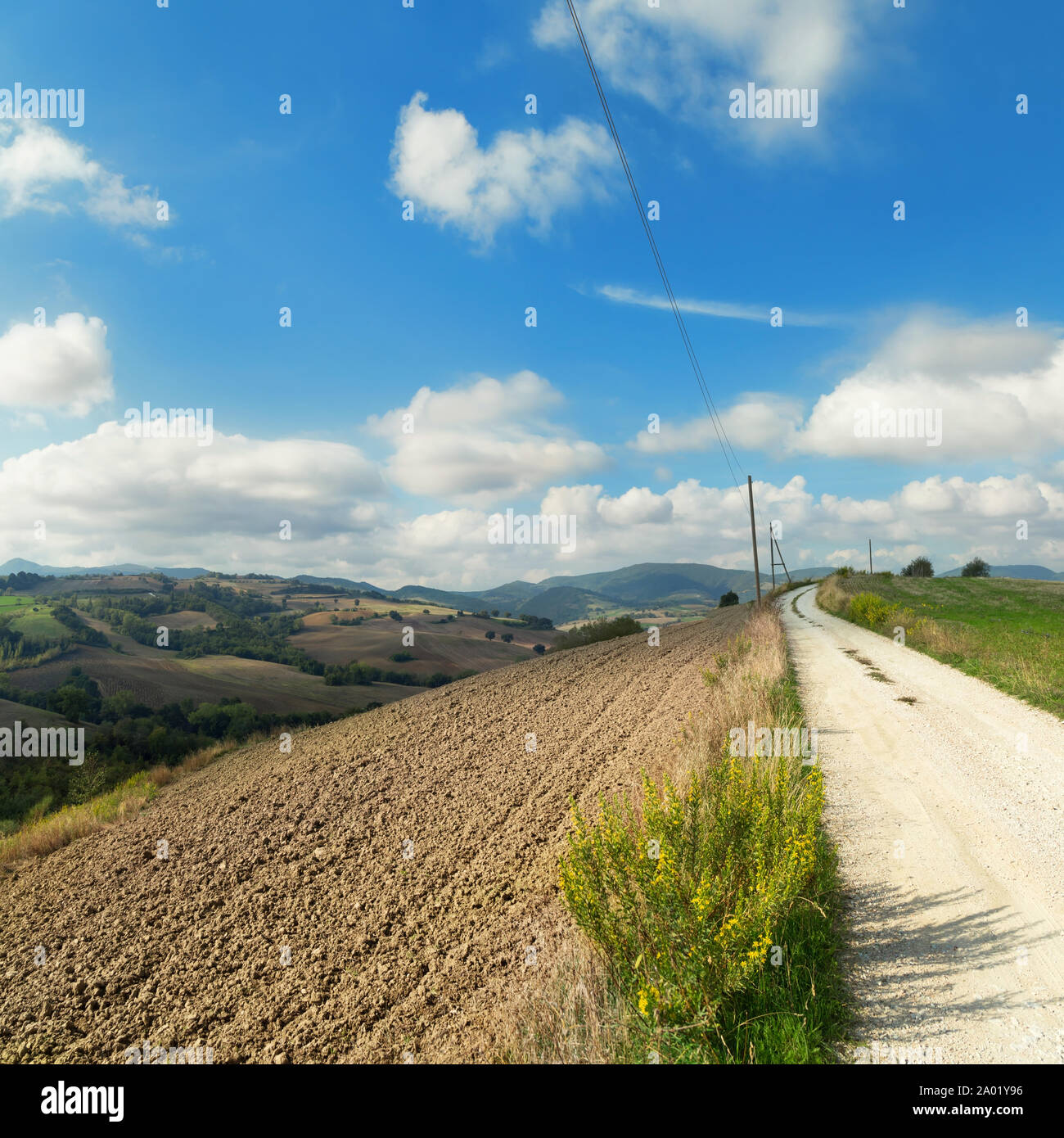 Paesaggio rurale con campi arati, cielo blu e nuvole all'orizzonte Foto Stock