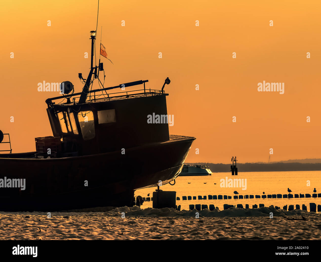 Silhouette del pescatore della barca ormeggiata al pontile di sabbia contro il cielo al tramonto Foto Stock