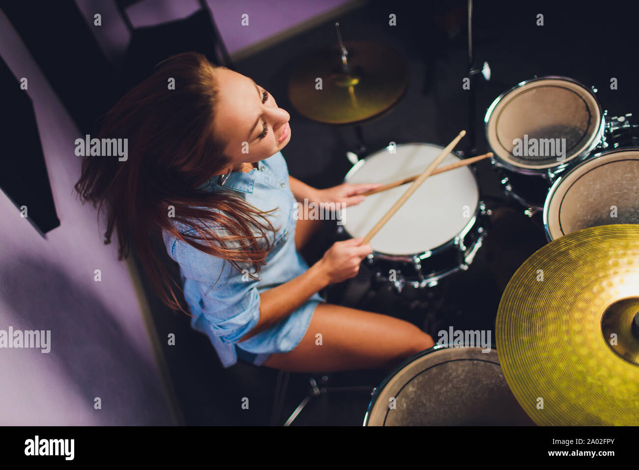 Fotografia di una femmina batterista suonare un drum set sul palco. Foto Stock