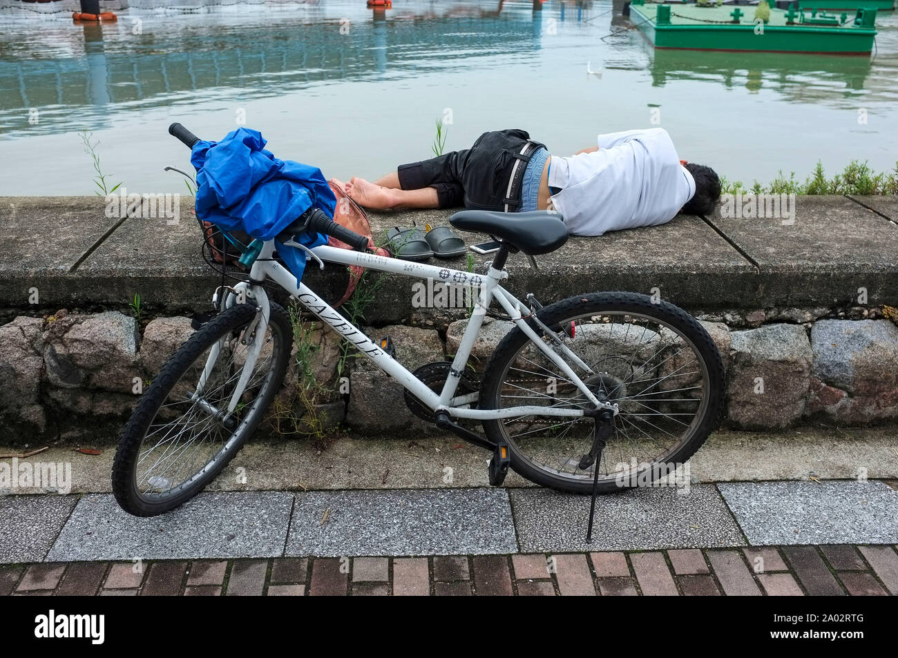 Uomo di dormire sulla banca del fiume di Fukuoka, Giappone. Foto Stock