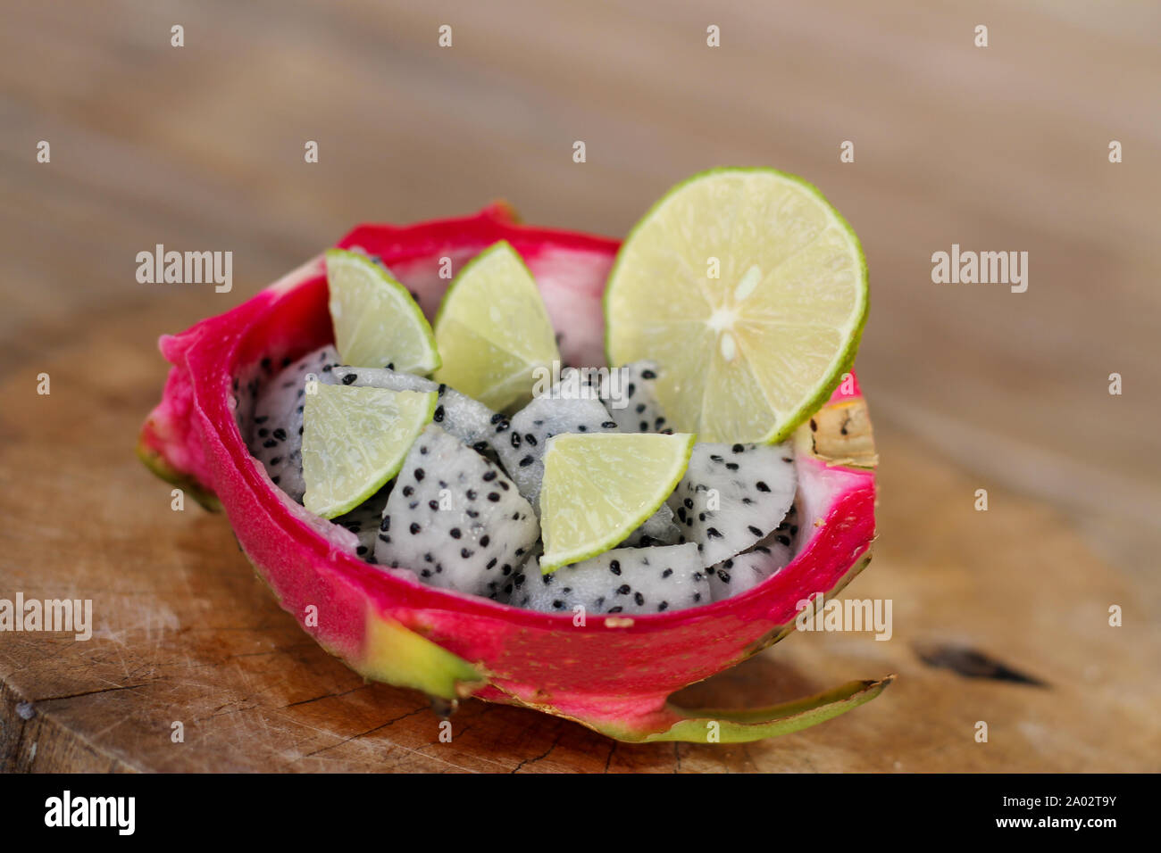 Frutta del drago affettata e fetta di lime in una ciocca di buccia di frutta del drago su sfondo vecchio tavolo di legno. Foto Stock