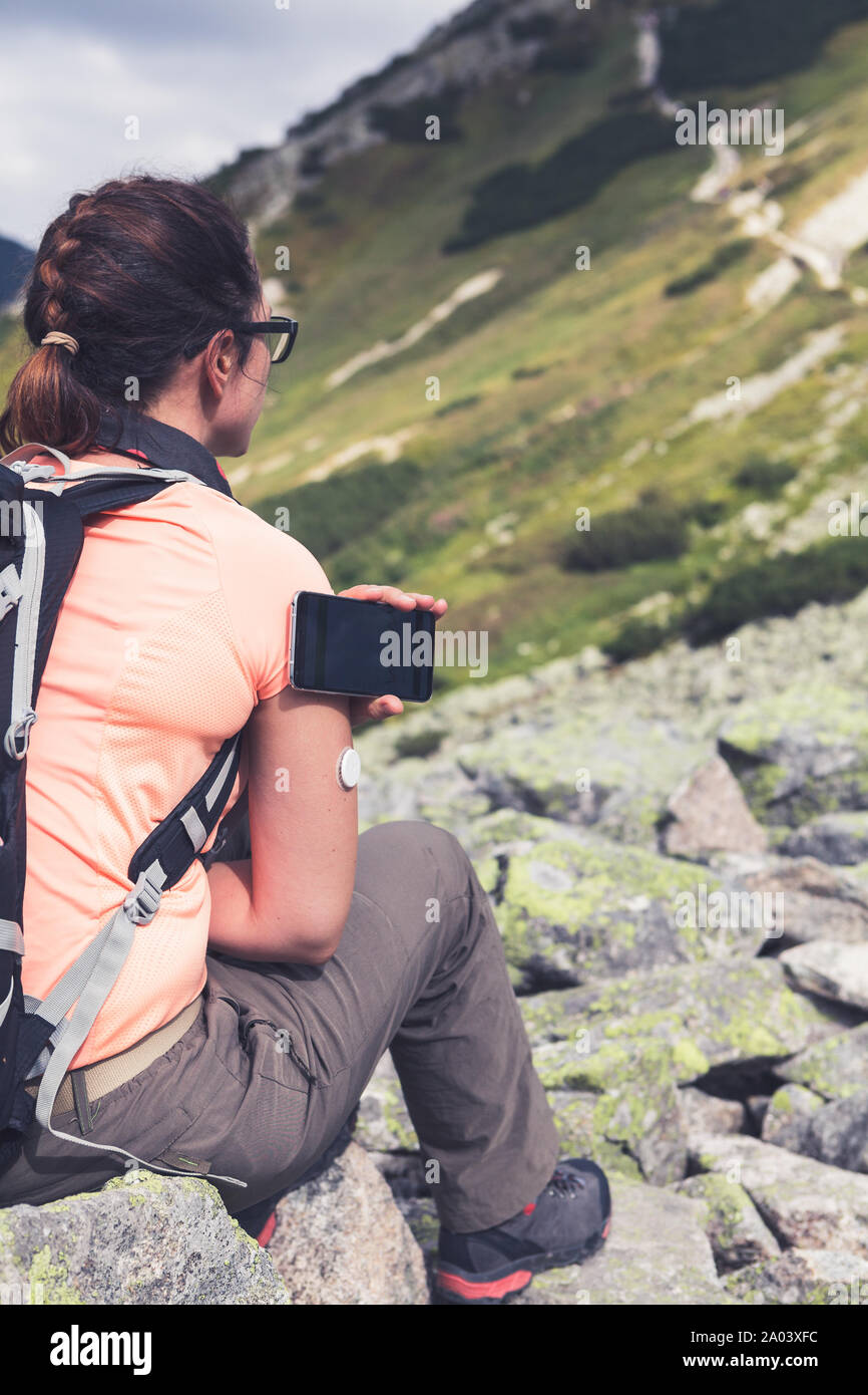 La vita attiva di diabetici, donna escursionismo e il controllo del livello di glucosio con un sensore remoto e il telefono cellulare, la nuova tecnologia di controllo del sensore per i livelli di glucosio Foto Stock