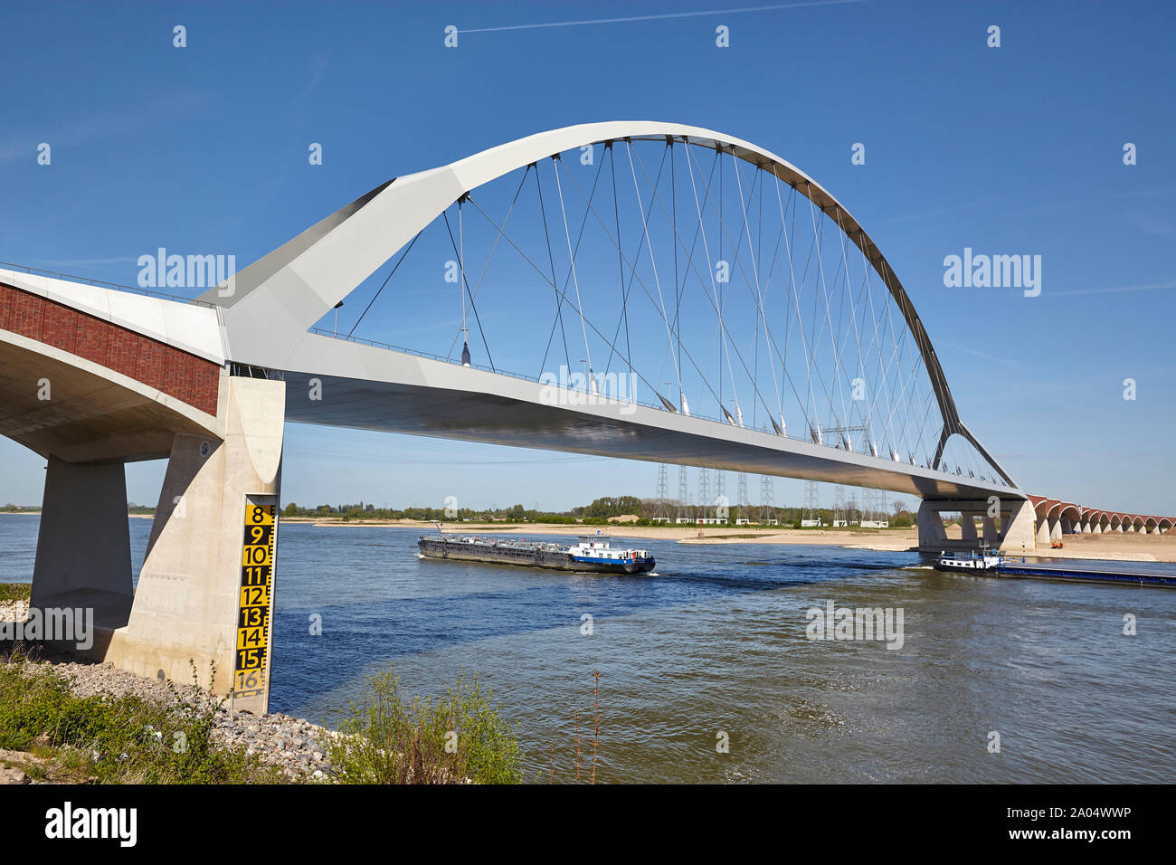 River Barge navigazione sotto un ponte denominato De Oversteek che attraversa il fiume Waal a Nijmegen nei Paesi Bassi Foto Stock