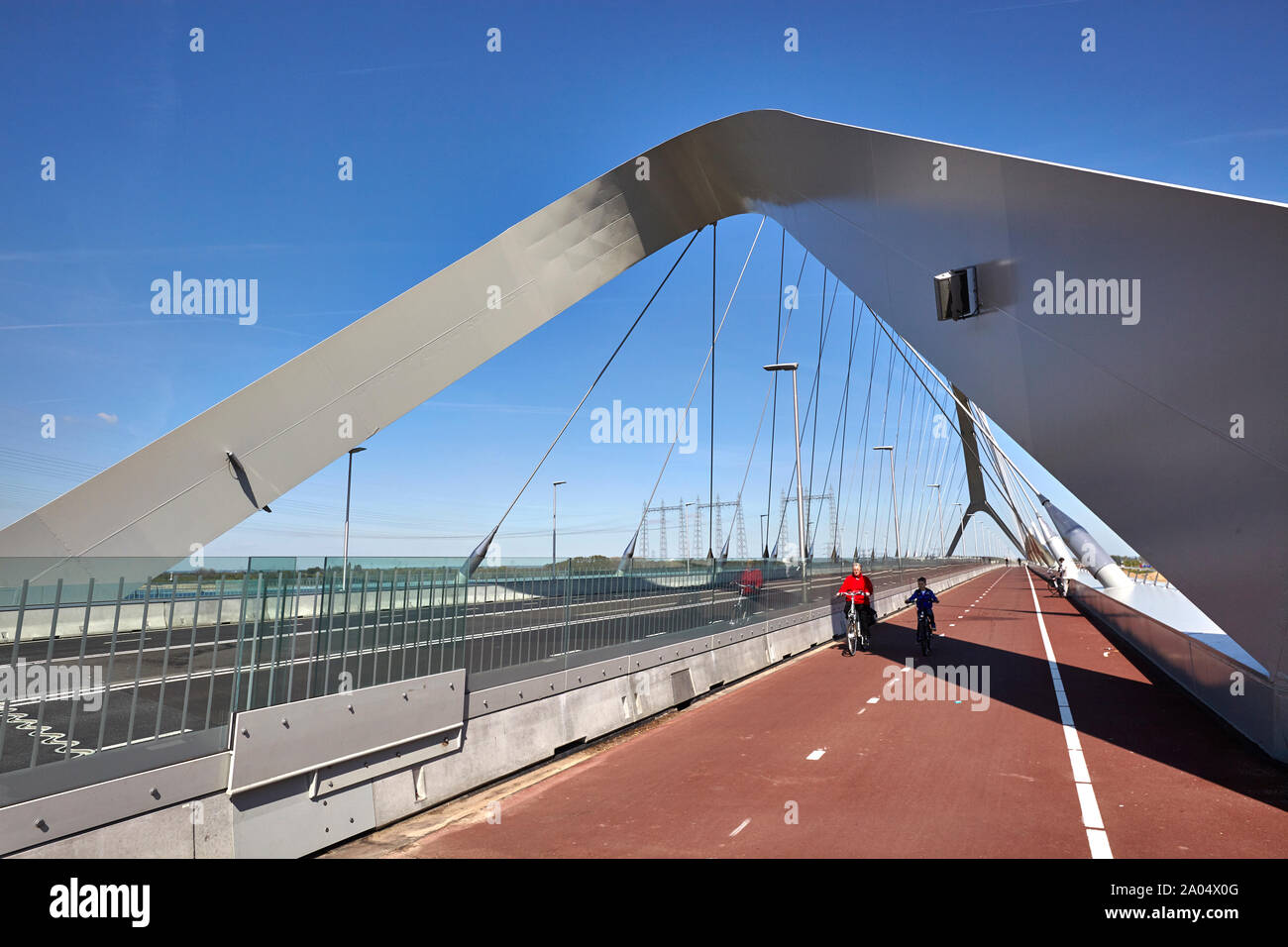 Una femmina e giovane ragazzo in bicicletta sul ponte di coperta di un ponte bowstring denominato De Oversteek che attraversa il fiume Waal a Nijmegen Foto Stock