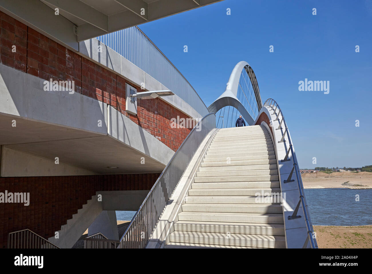 Calcestruzzo scalinata che conduce al ponte di un ponte bowstring denominato De Oversteek che attraversa il fiume Waal a Nijmegen Foto Stock