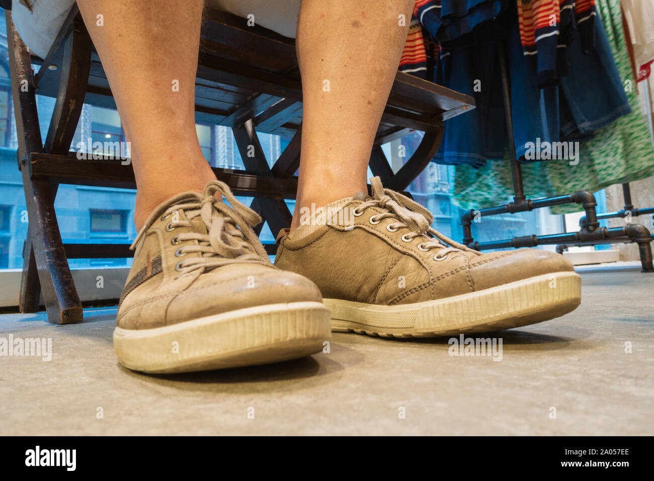 Scarpe, close up dei piedi e delle gambe di un uomo in tessuto store in attesa di partner. Foto Stock