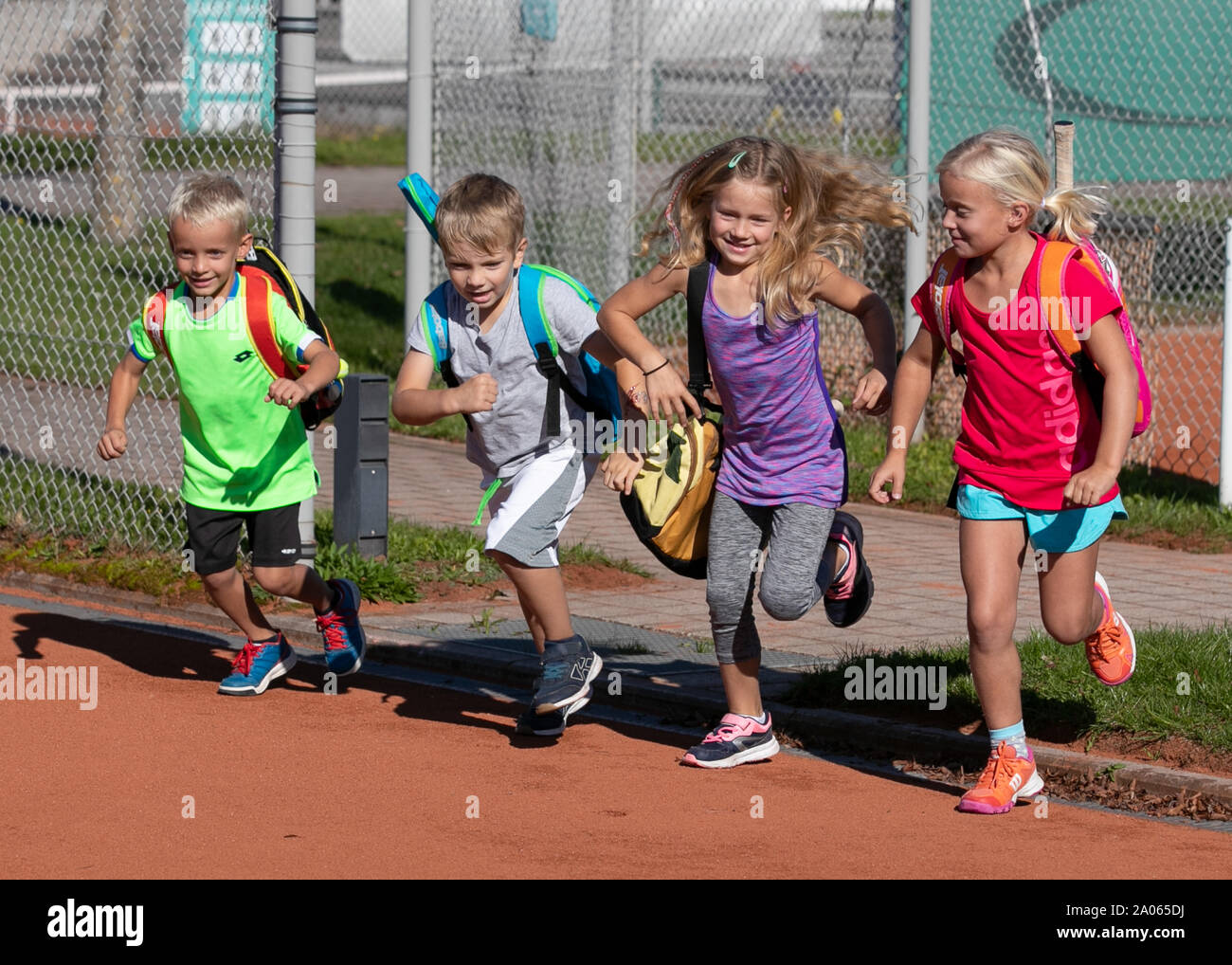 I bambini con i sacchetti e racchette in esecuzione sul campo da tennis Foto Stock