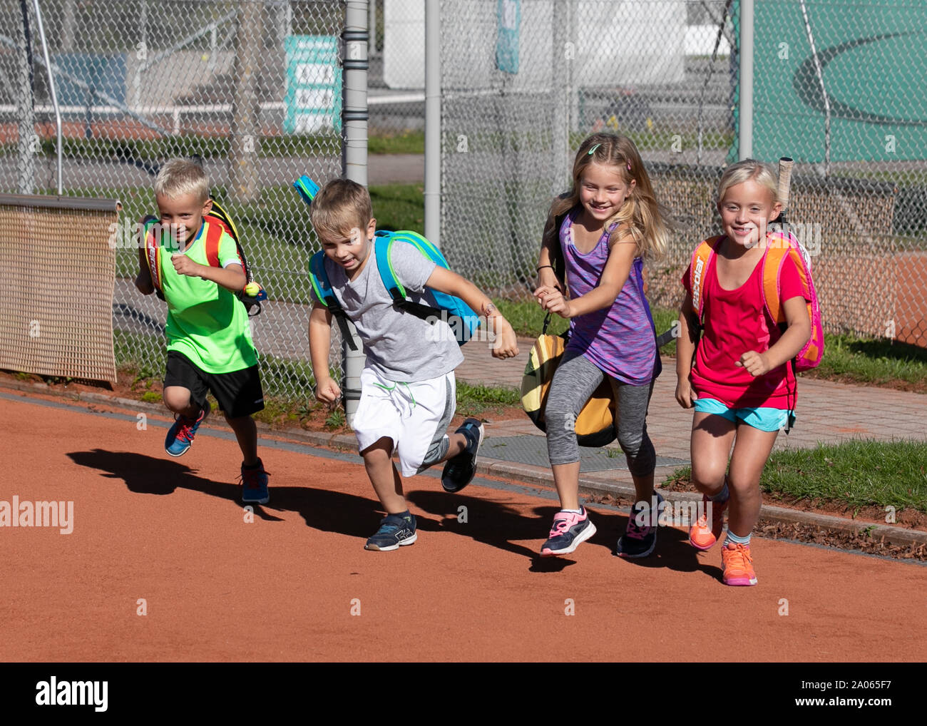 I bambini con i sacchetti e racchette in esecuzione sul campo da tennis Foto Stock