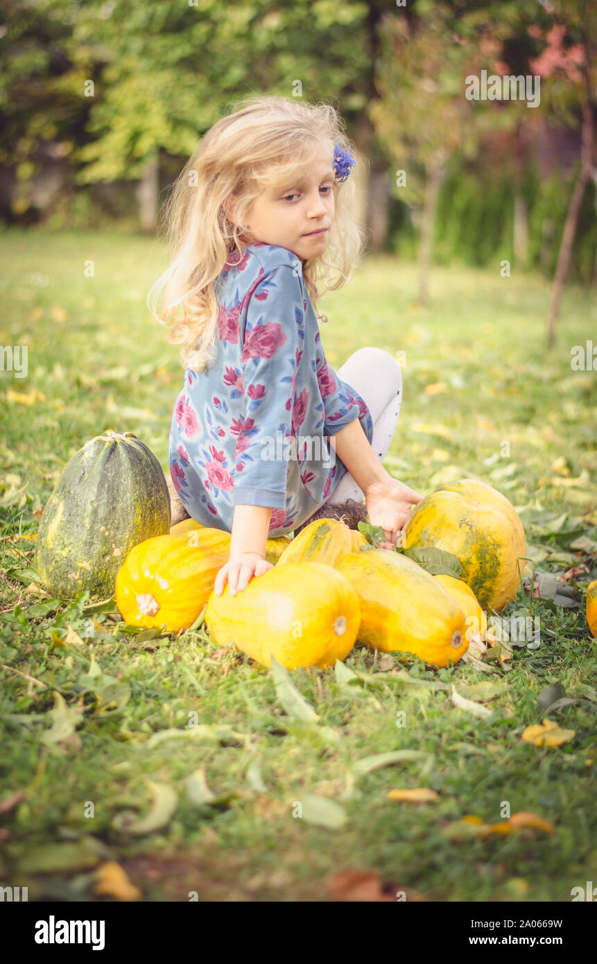 Bella ragazza bionda con orange autunno zucche in giardino Foto Stock