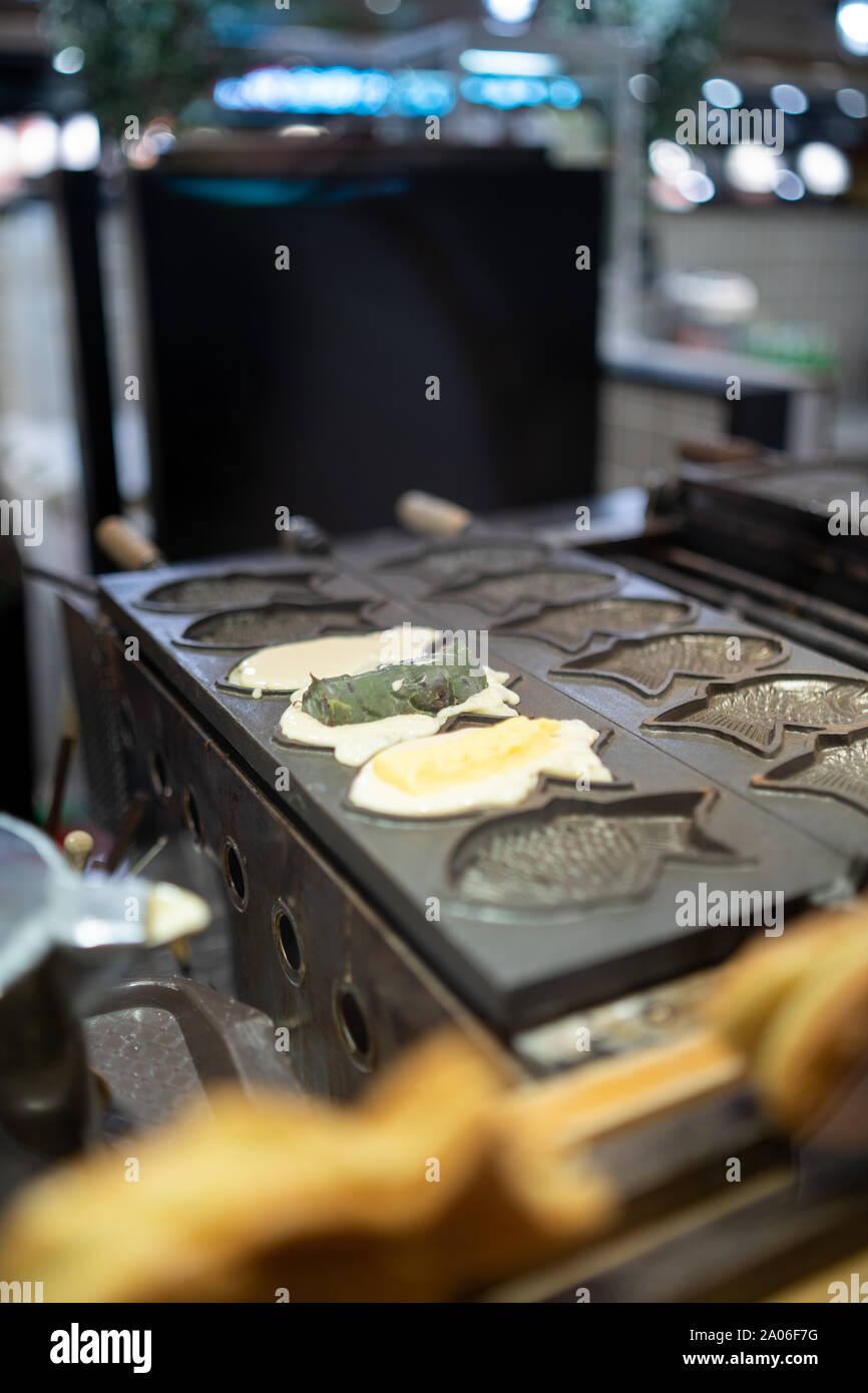 Kaohsiung, Taiwan: tradizionale giapponese / pesce Taiwanesi cialde sagomate con vari ripieni cottura in una ghisa pan Foto Stock