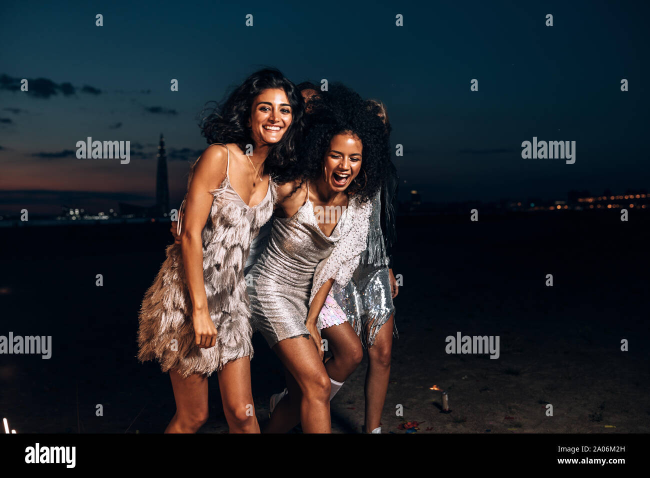 Amici di ridere insieme a piedi di notte all'esterno guardando la fotocamera Foto Stock
