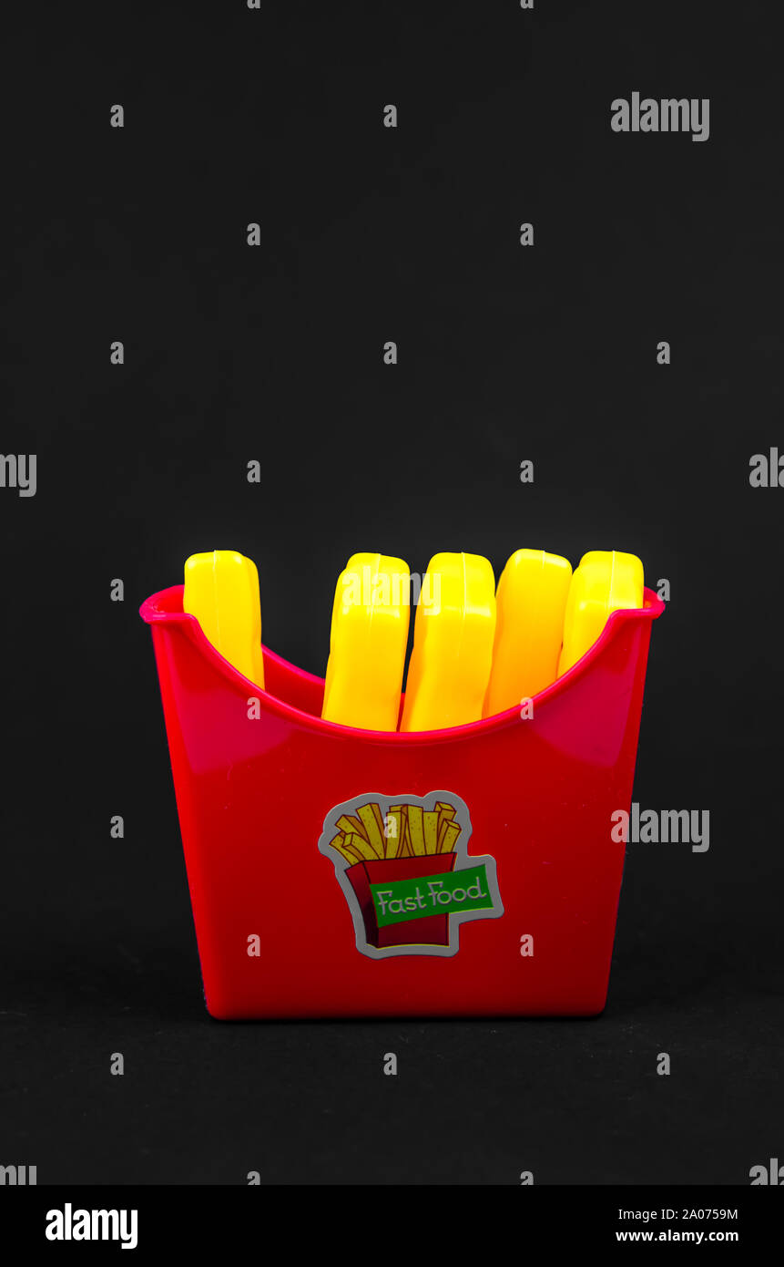 Il fast food. plastica patatine fritte su uno sfondo nero. copia spazio verticale. Foto Stock