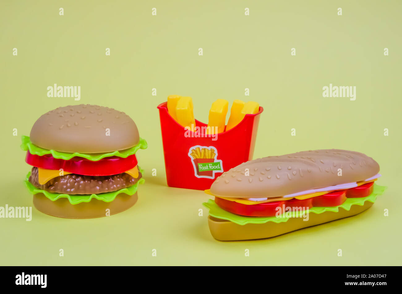 Il fast food. plastica hamburger, hot dog e patatine fritte su sfondo giallo Foto Stock