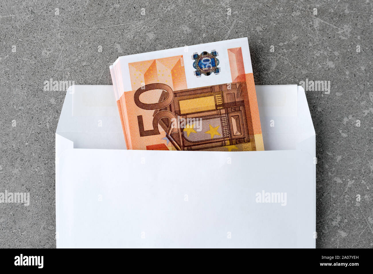 Busta bianca con un 50 euro bills. Pila di cinquanta euro note in open mail envelopeon calcestruzzo. Una delle banconote in euro piegato in una busta come un presente Foto Stock