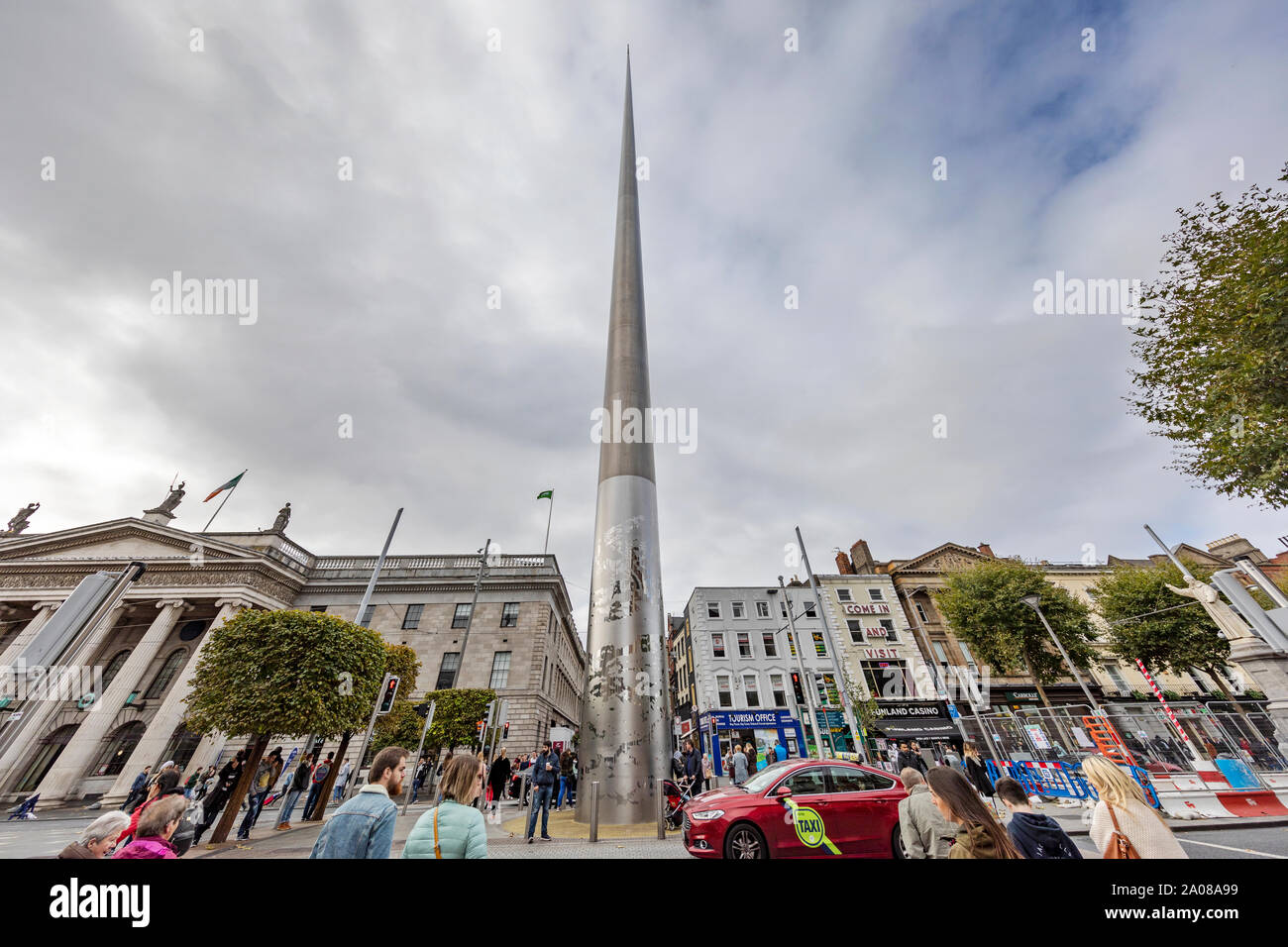 The spire on o'Connell Street Upper con molti negozi, pedoni, locali e turisti a piedi e lo shopping a Dublino, Irlanda. Foto Stock