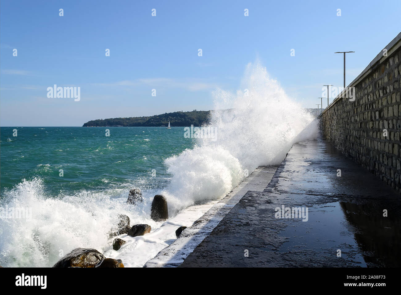 Spruzzi di mare onde infrangersi sulla scogliera. Percorso a piedi lungo la groyne è allagato con acqua di mare durante una tempesta di piccole dimensioni in una giornata di sole. Mar Nero. Foto Stock