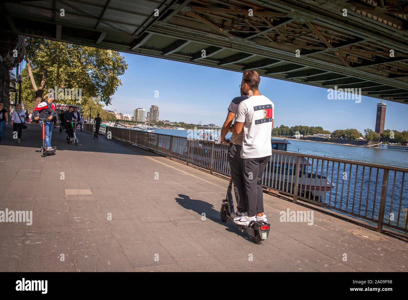 Giovani uomini su uno scooter elettrico della società calce sulle rive del fiume Reno, Colonia, Germania. junge Maenner auf Elektroscooter des Anbieter Foto Stock