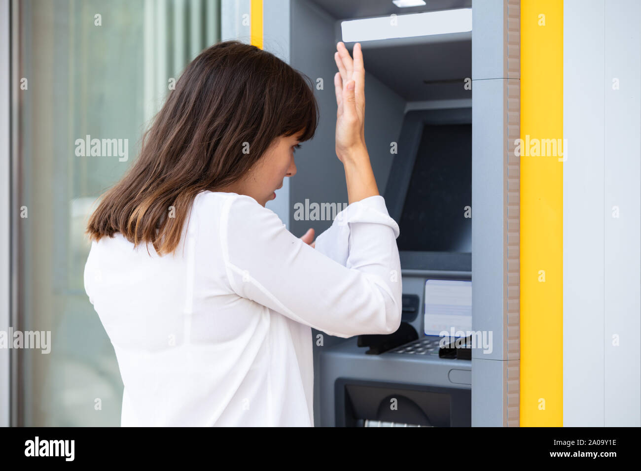Close-up di deluso giovane donna che guarda la banca ATM macchina dopo la verifica del saldo del conto Foto Stock