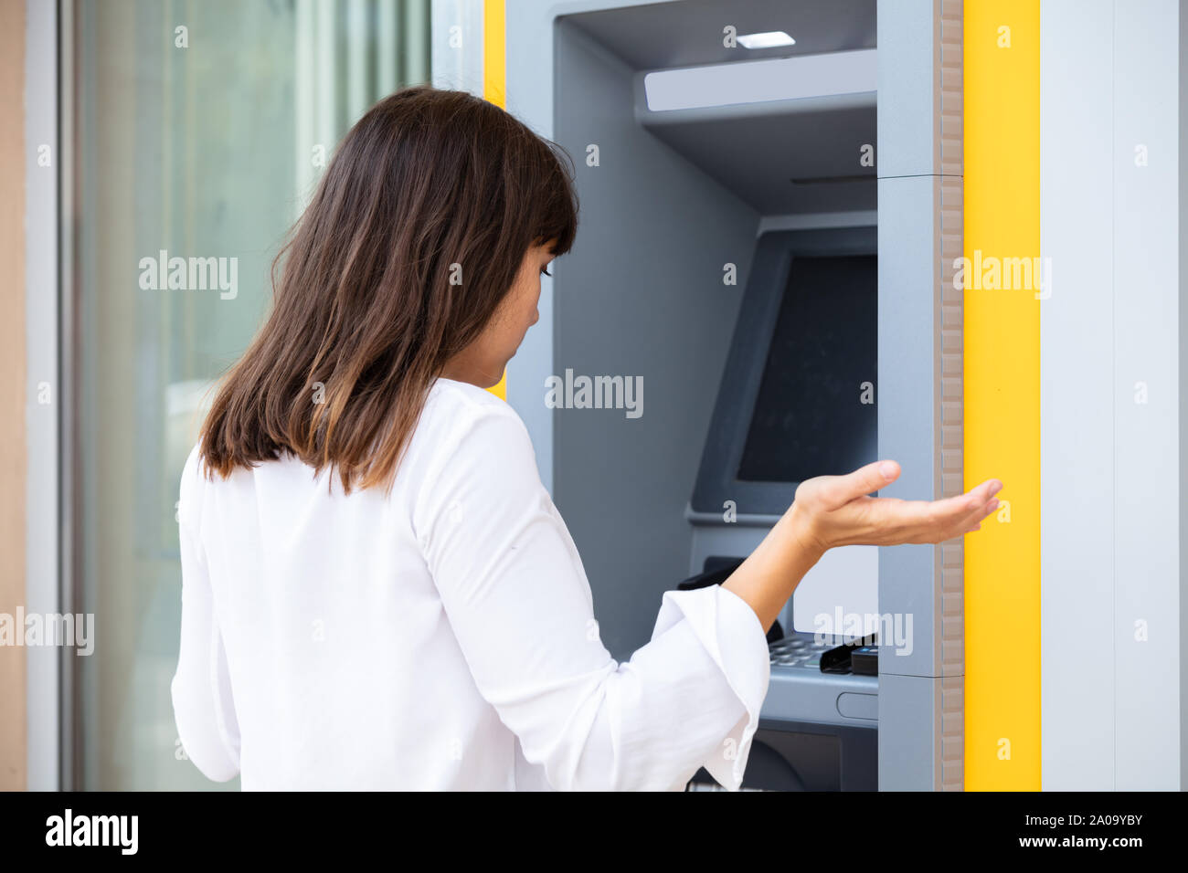 Close-up di deluso giovane donna che guarda la banca ATM macchina dopo la verifica del saldo del conto Foto Stock