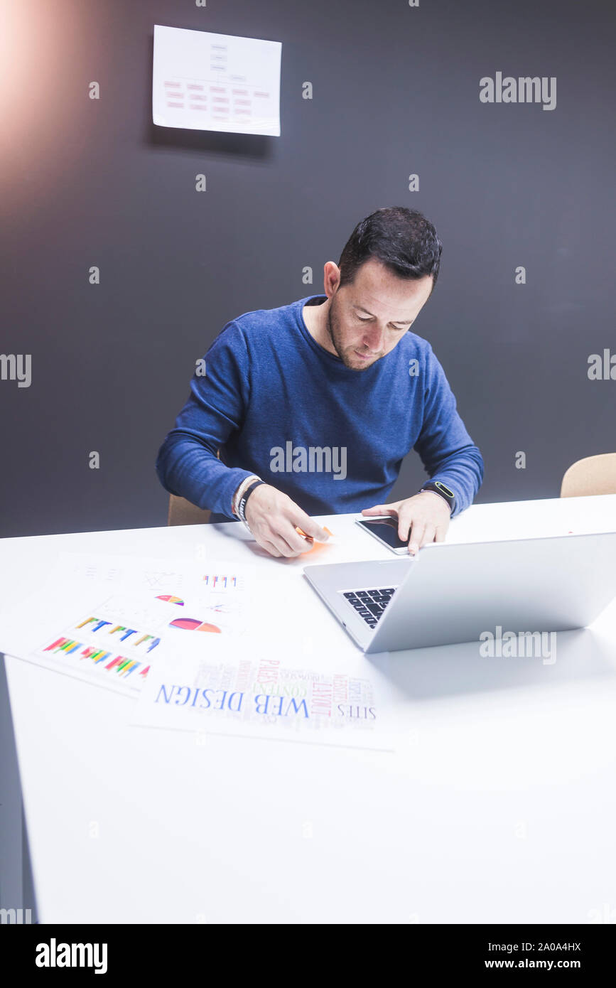 Uomo Barbuto lavorando sul computer portatile in ufficio Foto Stock