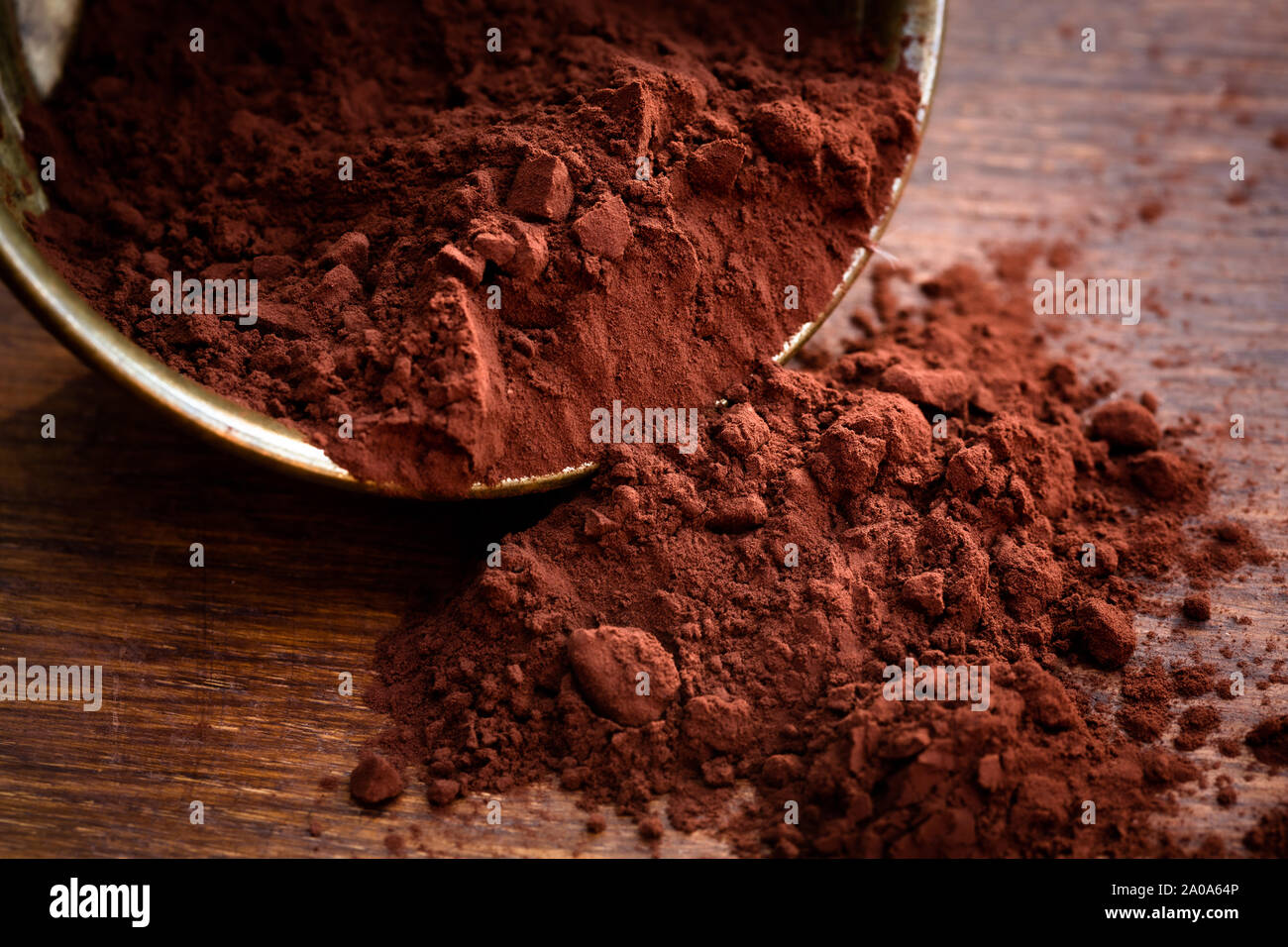 Cacao in polvere versato da un recipiente d'oro Foto Stock