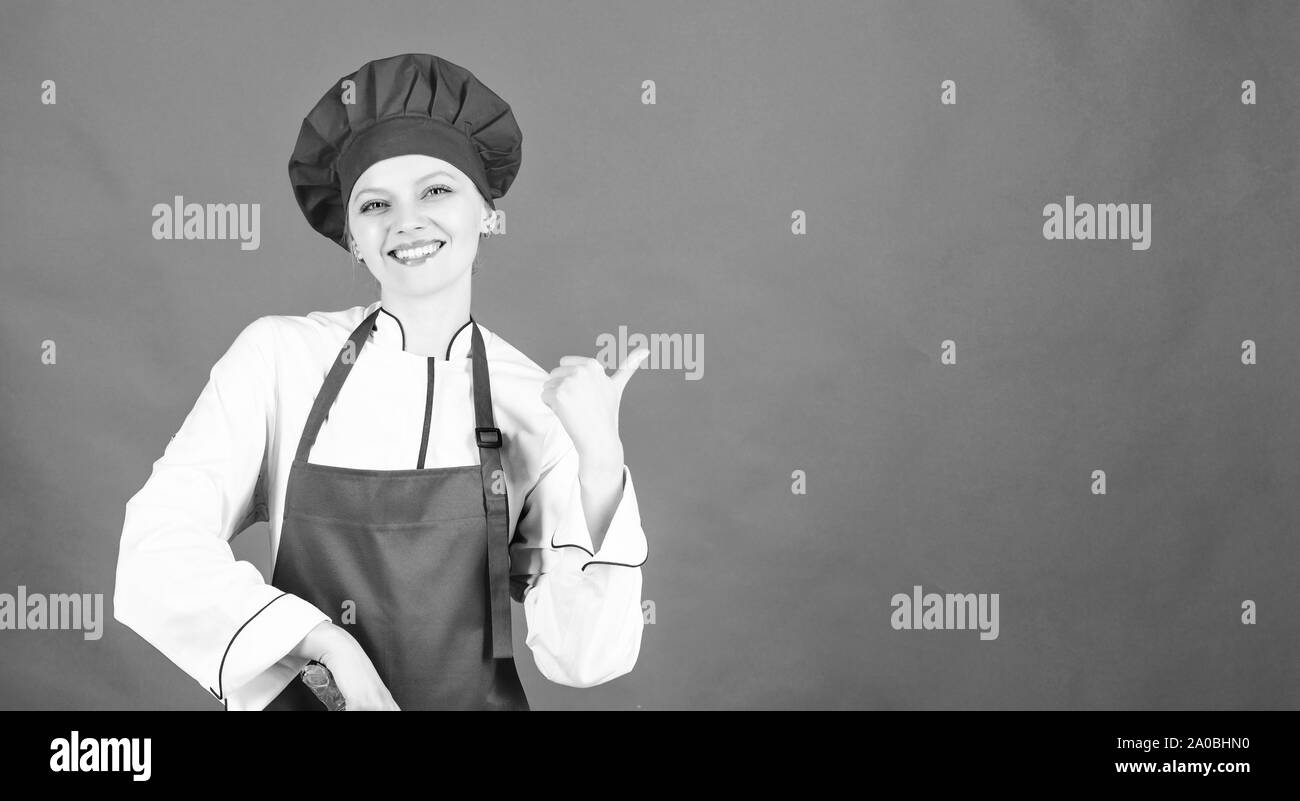 Donna in cook hat e grembiule. professionale chef in cucina. Cucina. donna felice per la cottura di alimenti sani da ricetta. La casalinga con coltello da cucina. copia di spazio. La mia colazione preferita. Foto Stock