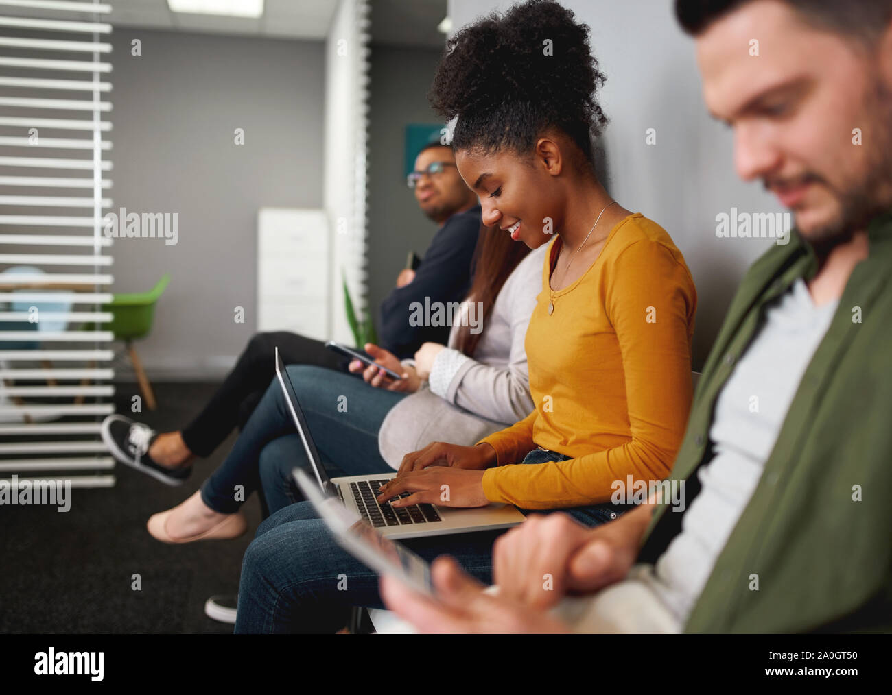 Concentrato sorridente giovane americano africano donna seduta in coda la preparazione per il lavoro a parlare delle assunzioni per Office Foto Stock