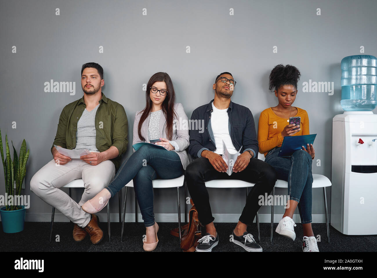 Diversi giovani annoiati richiedente seduti su una sedia in fila alla sala di attesa per il colloquio di lavoro in ufficio - gruppo di giovani del vero e autentico di persone Foto Stock