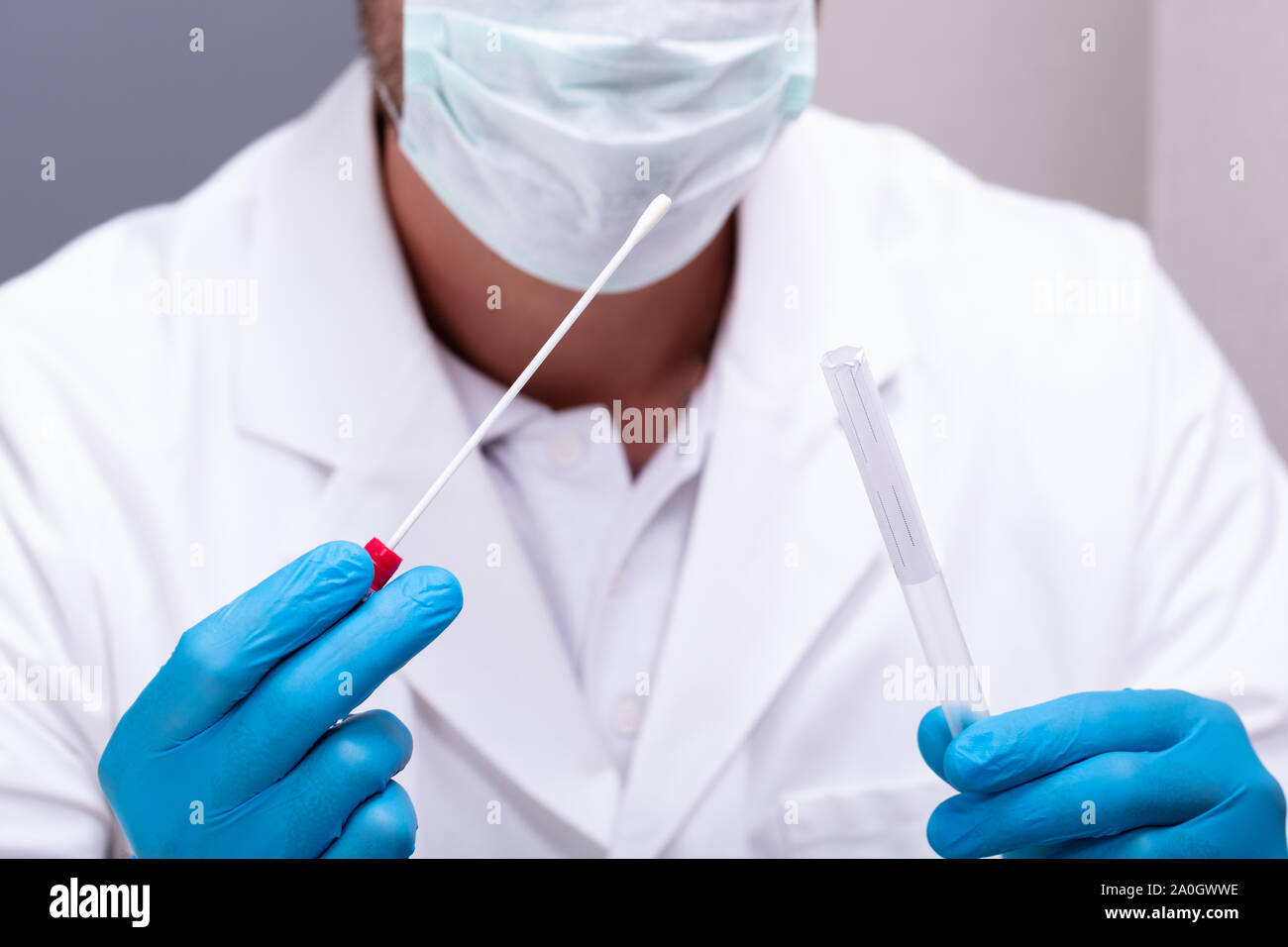 Medico maschio indossando guanti blu tenendo un batuffolo di cotone e DNA tubo di prova Foto Stock