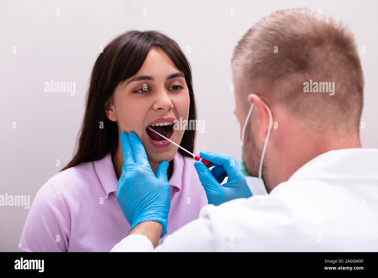 Vista posteriore di un medico di sesso maschile prendendo un fluido corporeo campione per il test del DNA Foto Stock