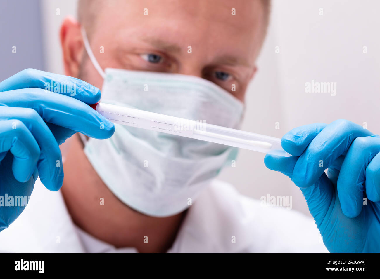 Medico maschio azienda boccale un batuffolo di cotone e il tubo di prova pronto a raccogliere il DNA Foto Stock