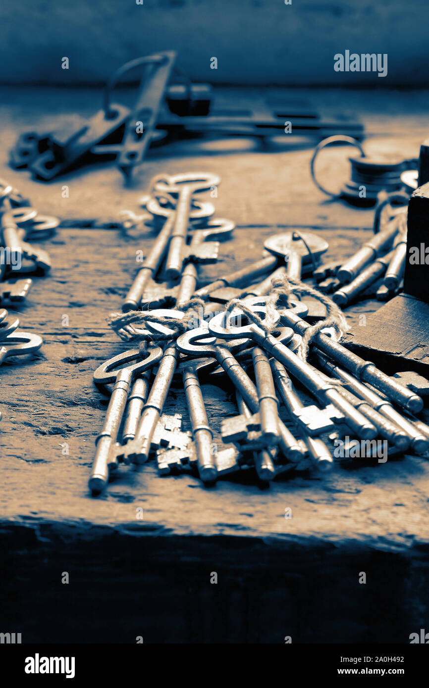 Grappolo di vecchie chiavi su un banco di lavoro in legno a un fabbro. Con colore di tonificazione Foto Stock