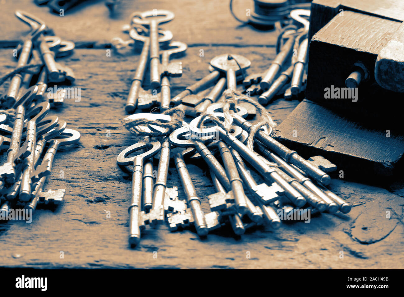 Grappolo di vecchie chiavi su un banco di lavoro in legno a un fabbro. Con colore di tonificazione Foto Stock