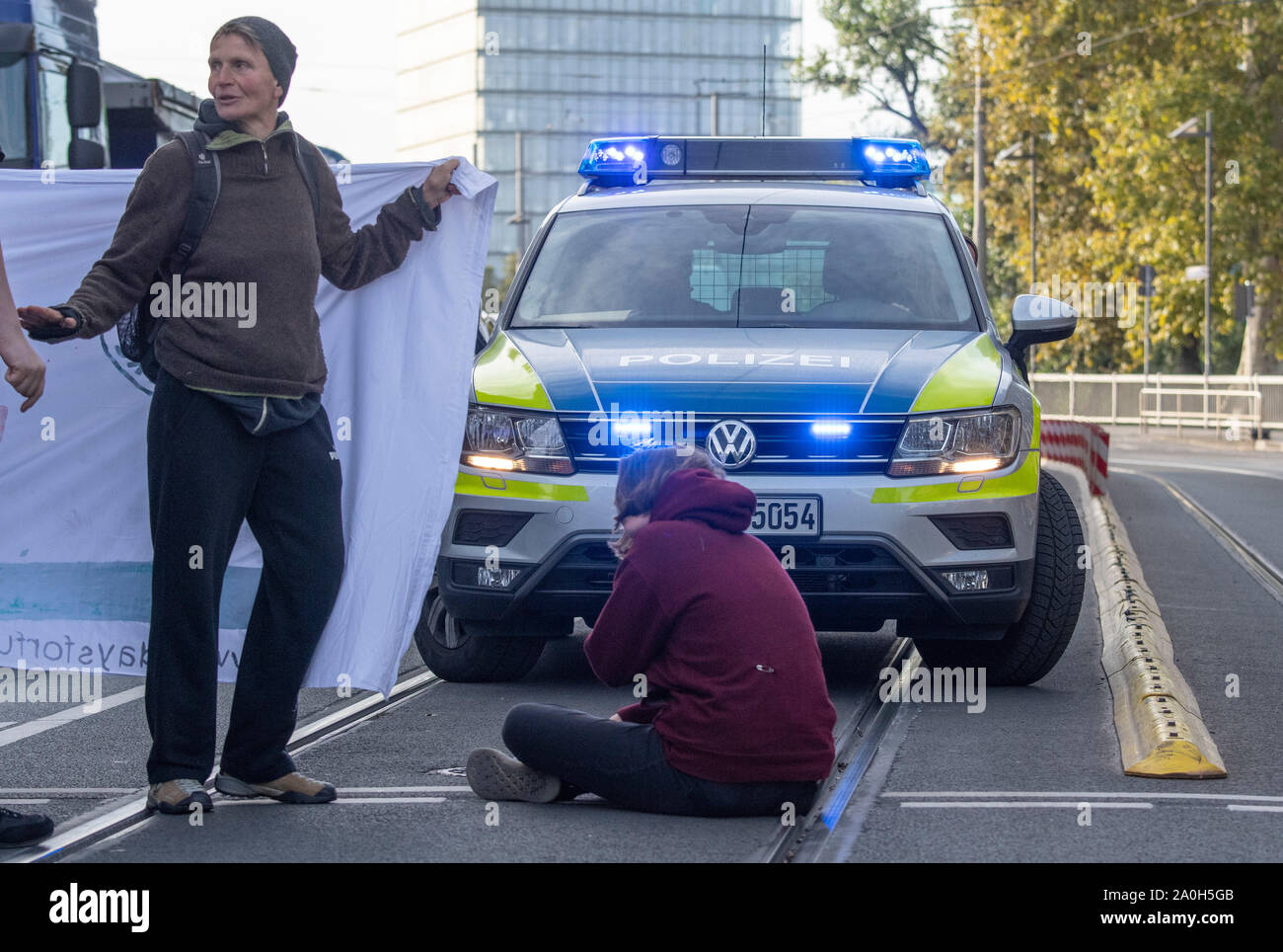 Francoforte, Germania. Il 20 settembre 2019, Assia, Frankfurt/Main: dimostranti di vari gruppi di azione di bloccare il traffico su Baseler Platz; un dimostrante è seduto sulla corsia nella parte anteriore di una macchina della polizia. I dimostranti seguire la chiamata del movimento il venerdì per il futuro e vogliono lottare per di più la protezione del clima. Essi vogliono supportare le chiamate per gli scioperi e manifestazioni di protesta in tutto il mondo. Foto: Boris Roessler/dpa Credito: dpa picture alliance/Alamy Live News Foto Stock