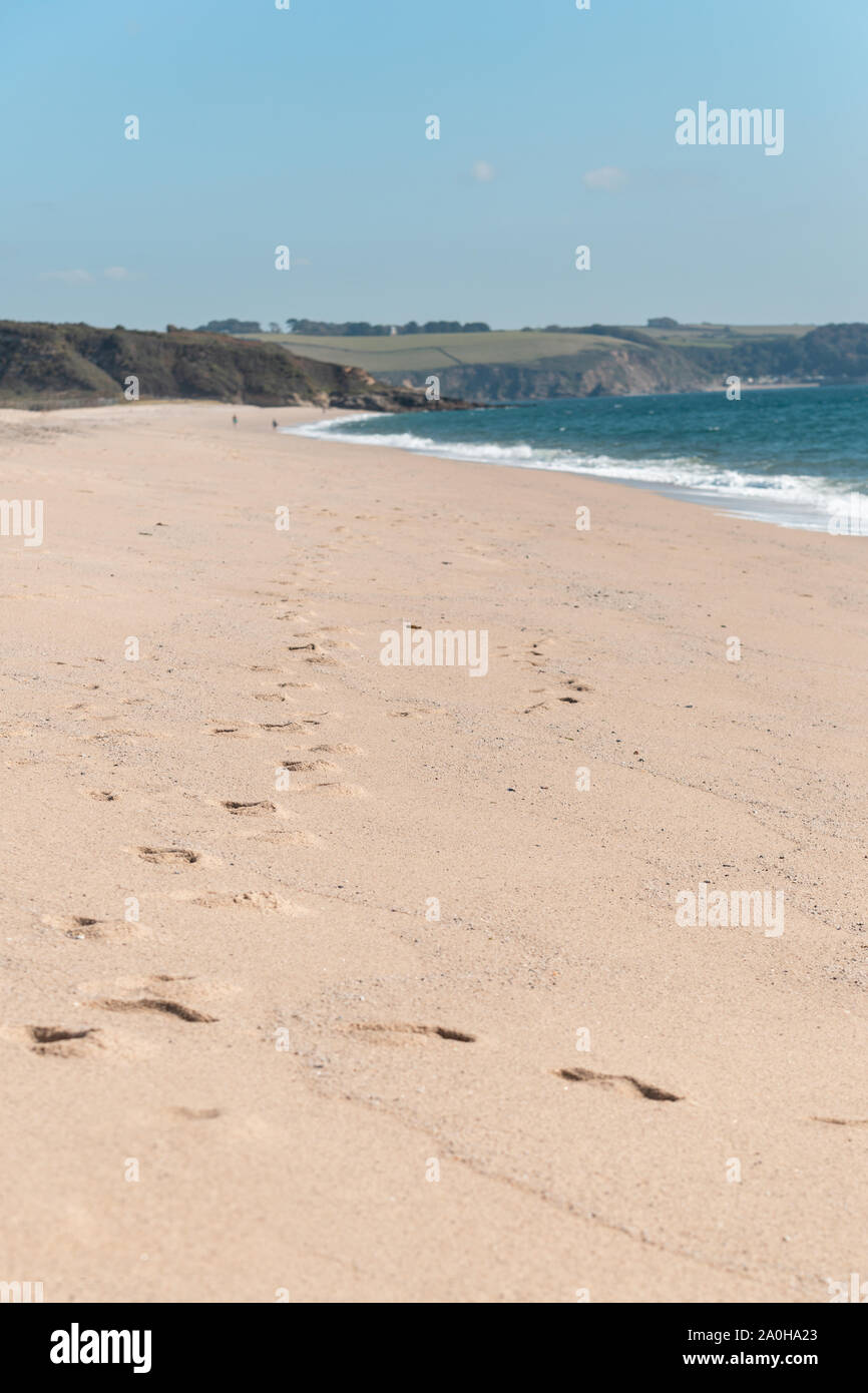 Spiaggia scena con orme nella sabbia e l'oceano blu. Cornish beach in Cornwall Regno Unito. Verticale. Intenzionale messa a fuoco poco profonde. Foto Stock