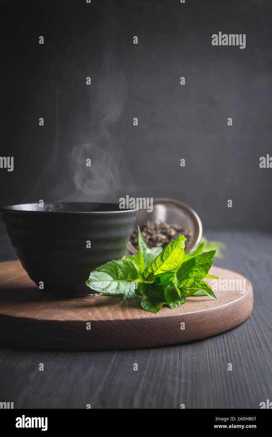 Il tè caldo con la menta in tazza nera su sfondo scuro. Il tè cinese. Asian ancora in vita. Foto Stock